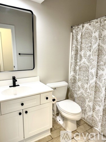 A white bathroom with a sink, toilet and shower curtain.