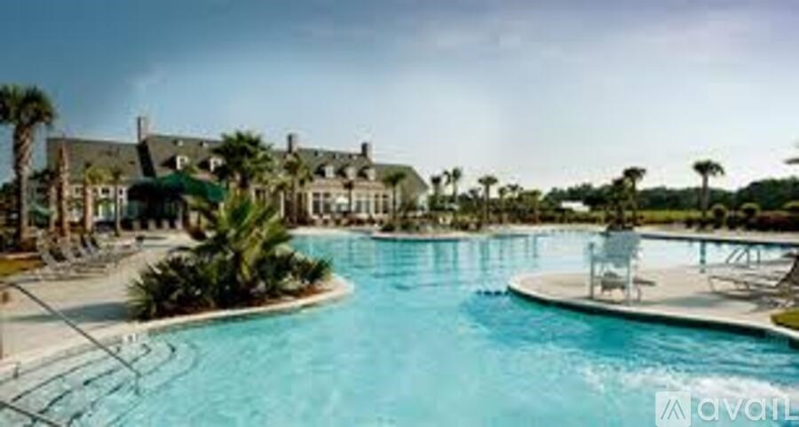 A large swimming pool with a water slide and a building in the background.