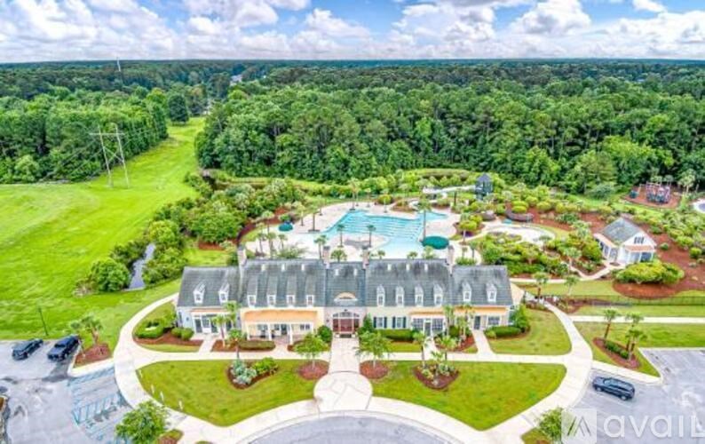 A large house with a pool is surrounded by a well-manicured lawn and trees.