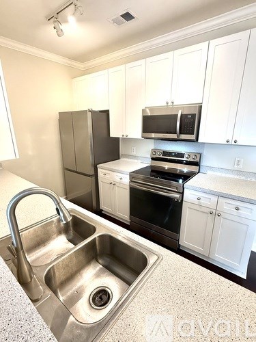 A kitchen with a sink, stove, and refrigerator.