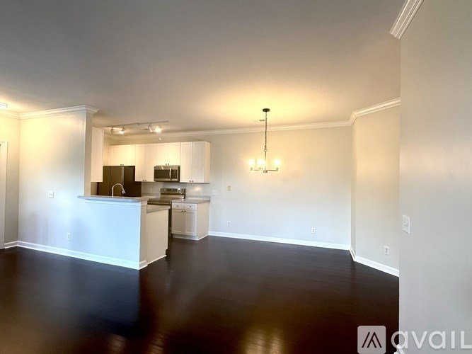 A spacious kitchen and living room with white walls and dark flooring.
