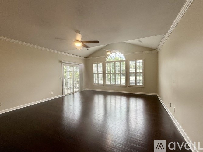 A spacious room with wooden floors and a ceiling fan.