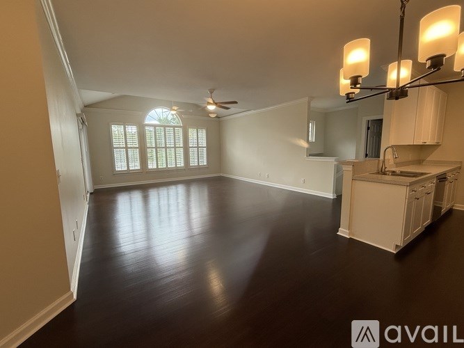A spacious room with a kitchenette and a ceiling fan.