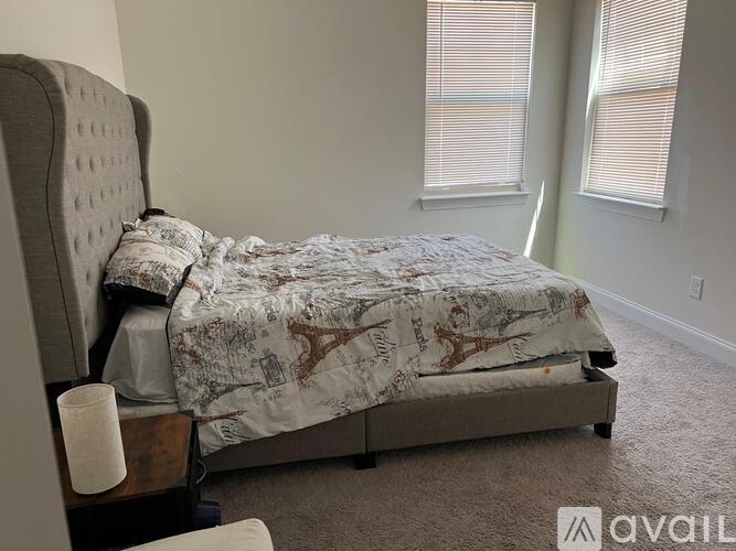 A bed with a patterned comforter and a nightstand with a lamp on it.