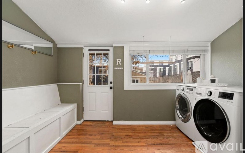 A laundry room with a washer and dryer and a white couch.