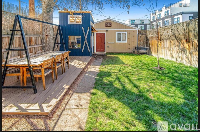 A backyard with a wooden deck and a blue shed.