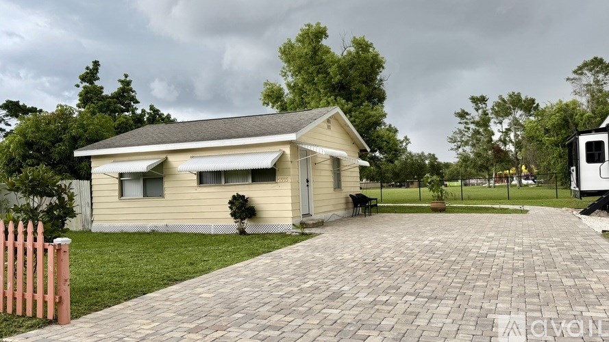 A house with a brick driveway and a pink fence.