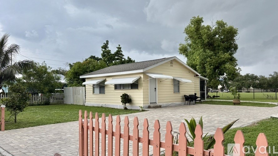 A house with a pink picket fence in front of it.
