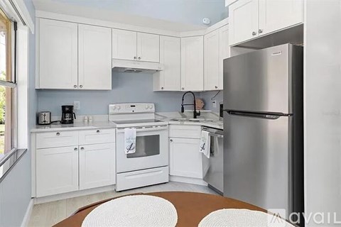 A kitchen with white cabinets and appliances.