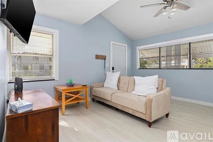 A living room with a beige couch, a wooden table, and a ceiling fan.
