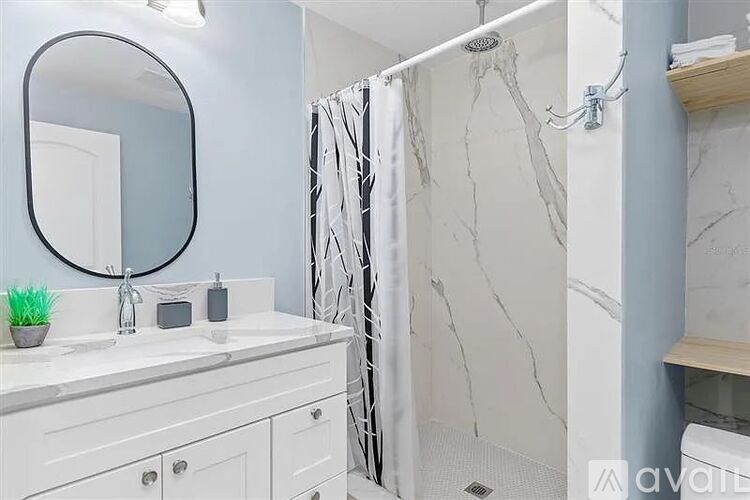 A bathroom with a marble shower and a white vanity.