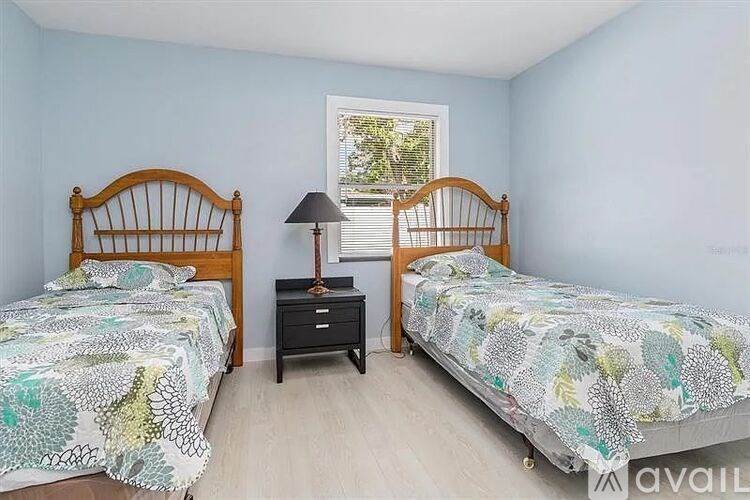 Two beds with matching headboards and a nightstand with a lamp between them.