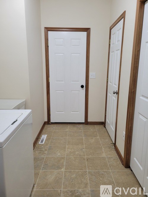 A white door with a black handle is in the middle of a hallway.
