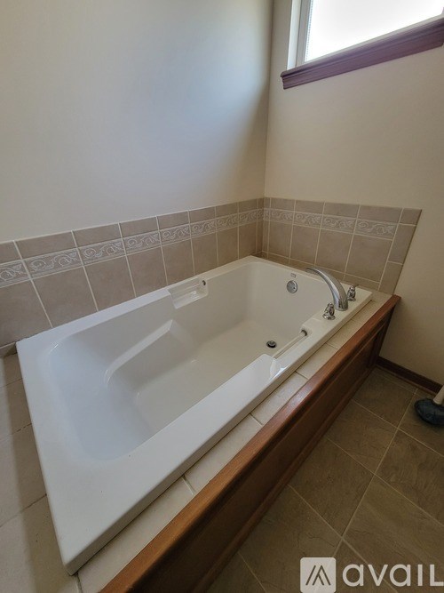 A white bathtub with a brown wooden frame in a bathroom.