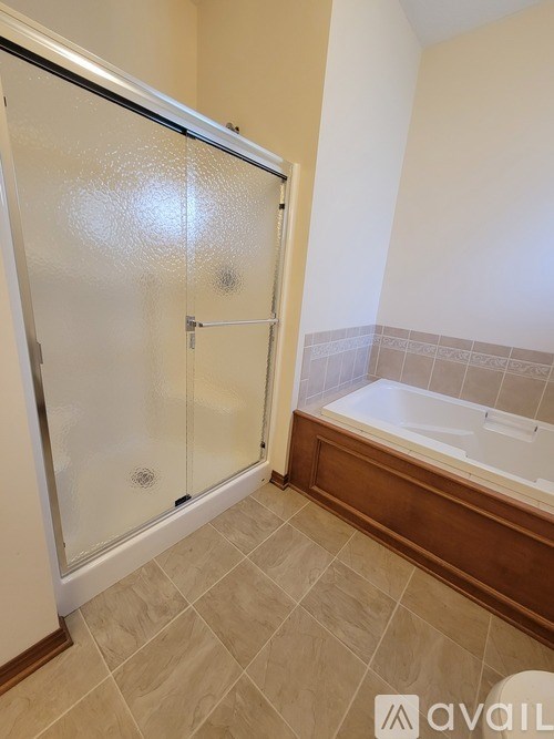 A bathroom with a glass shower door and a bathtub.