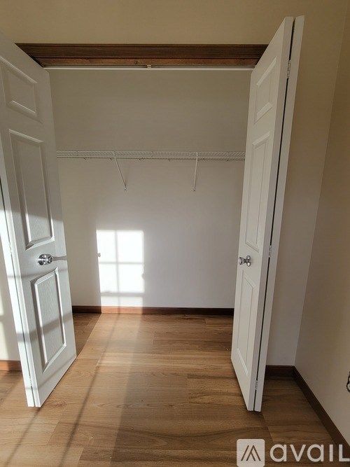 A room with a white door and wooden floor.