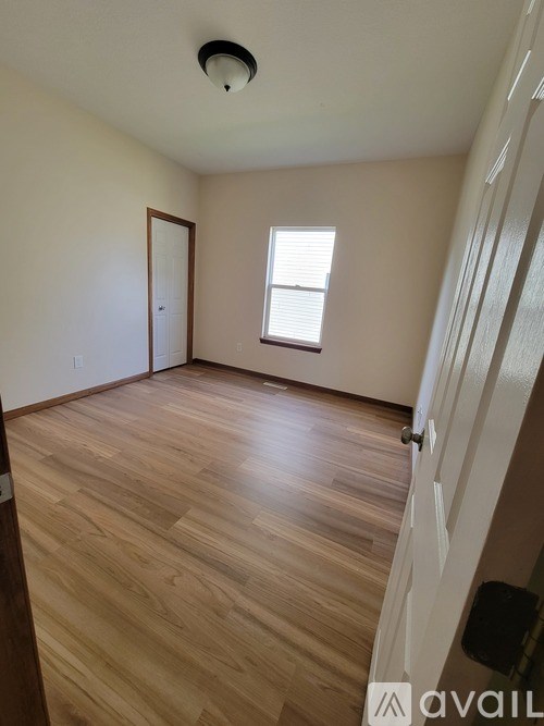 A room with wooden flooring and a window with blinds.