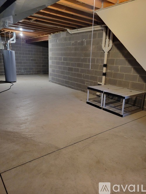 A room with a concrete floor and a bench under a staircase.