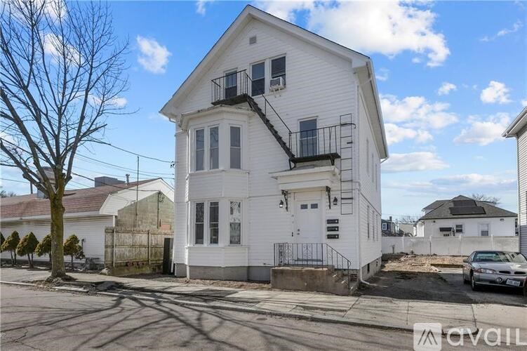 A white two-story house with a balcony on the second floor.