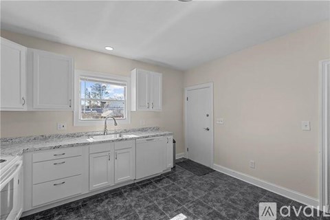 A kitchen with white cabinets and a marble countertop.