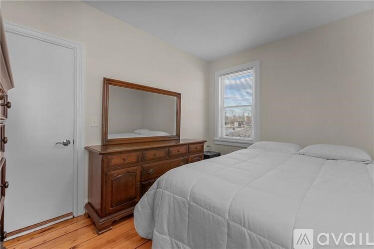 A bedroom with a bed, dresser, and mirror.