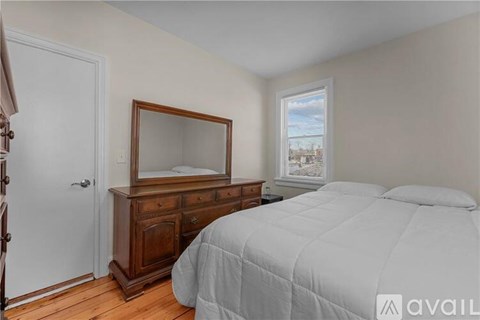 A bedroom with a bed, dresser, and mirror.