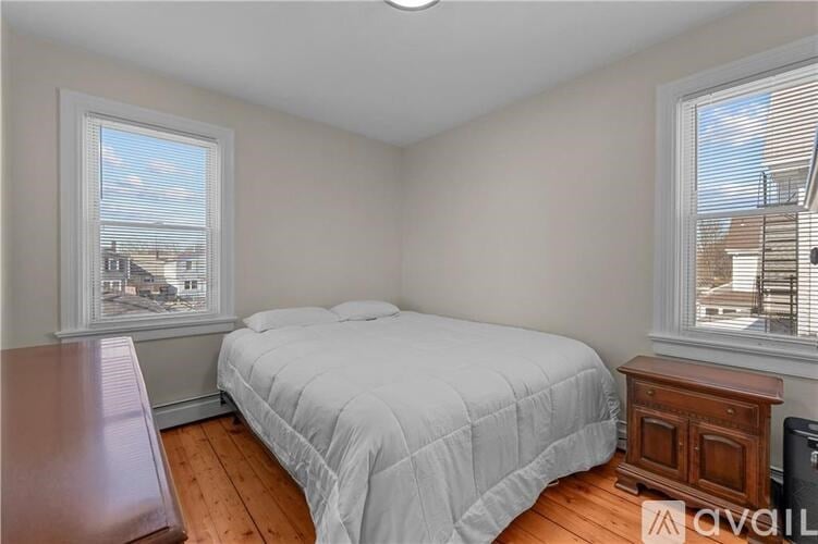 A bedroom with a bed, a window with blinds, and a wooden nightstand.