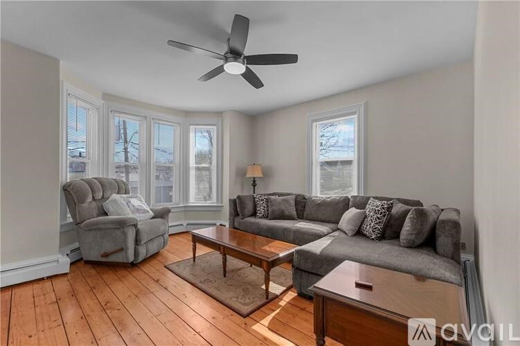 A living room with a grey couch, a grey armchair, a wooden coffee table, and a ceiling fan.
