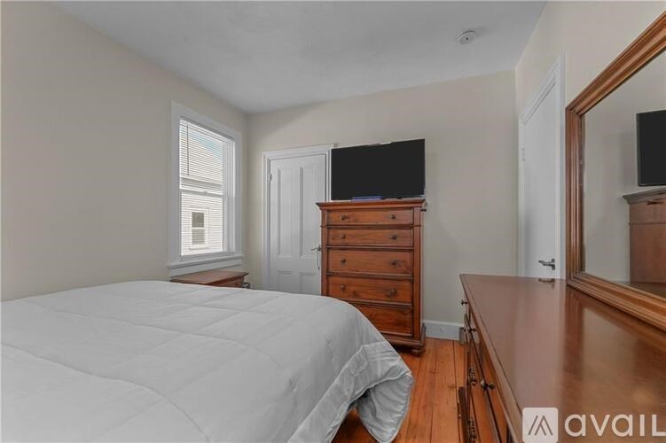 A bedroom with a bed, dresser, and mirror.