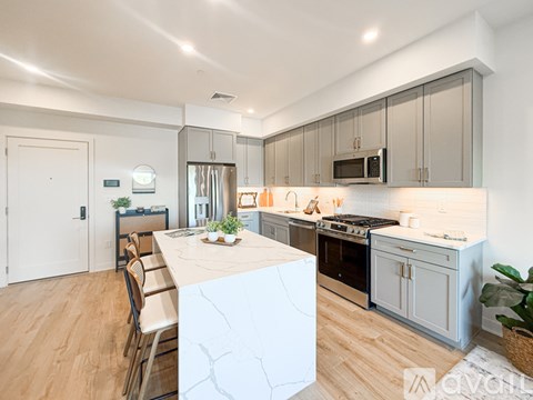 A modern kitchen with a white marble island and wooden floors.