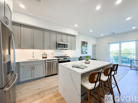 A kitchen with a white island and wooden chairs.