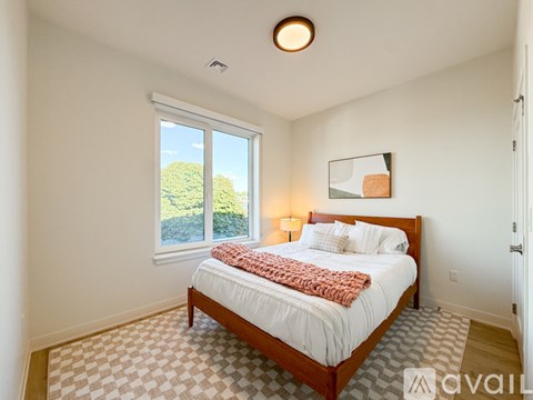 A bedroom with a large bed and a window overlooking a green landscape.