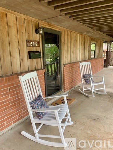 Two white rocking chairs are placed on a porch.