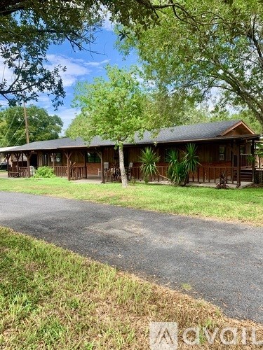 A wooden building with a porch and a tree in front.