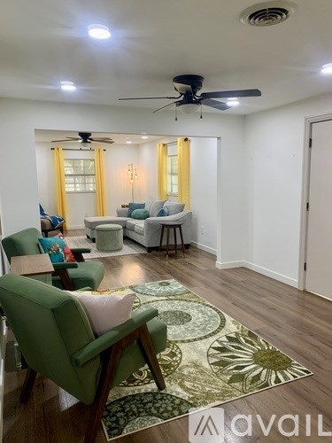 A living room with a green chair and a rug with a leaf design.