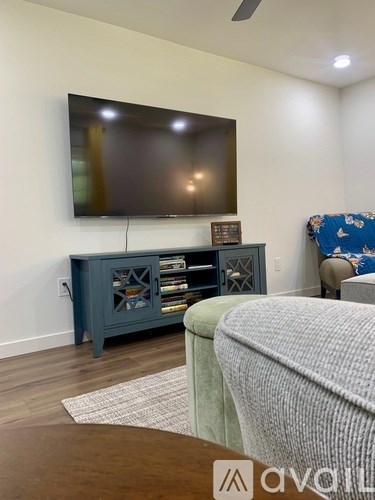 A living room with a flat screen TV mounted on the wall and a cabinet below it.