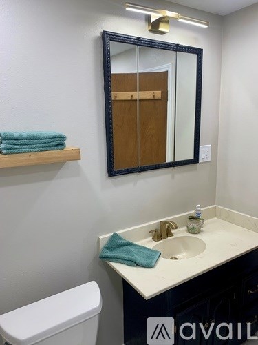 A bathroom with a white toilet, a sink with a blue towel on it, and a mirror above the sink.