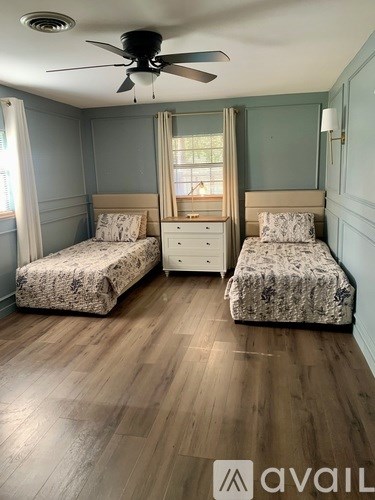 A bedroom with two beds and a ceiling fan.
