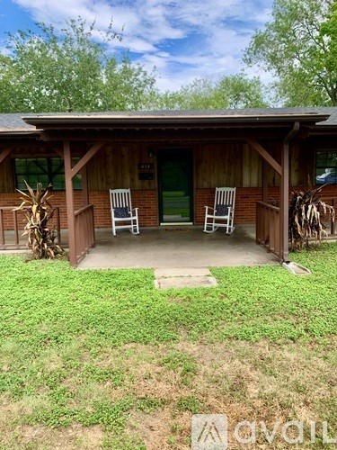 A wooden house with a porch and two chairs.