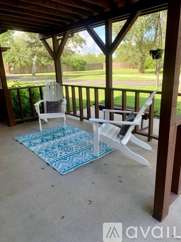 A white chair is on a porch with a blue and white rug.