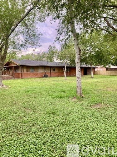 A house with a green lawn and a tree in front of it.