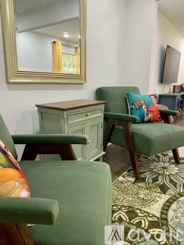 A green chair with a wooden desk and a mirror above it.