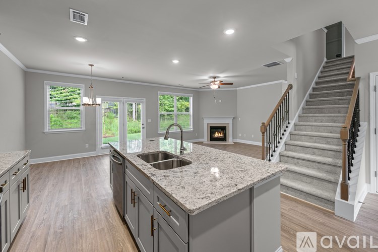 A modern kitchen with a large island and stairs leading to the upper floor.