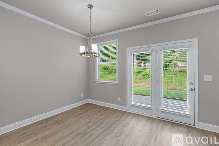 A room with a chandelier, two windows with blinds, and a door leading outside.