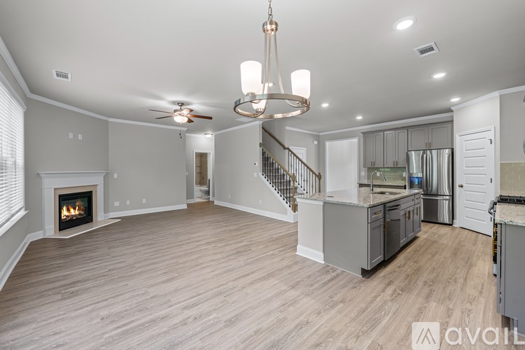 A large open living space with a fireplace and a staircase leading to the upper level.
