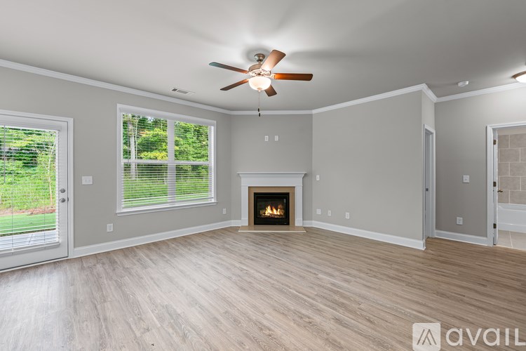 A spacious living room with a fireplace and a ceiling fan.