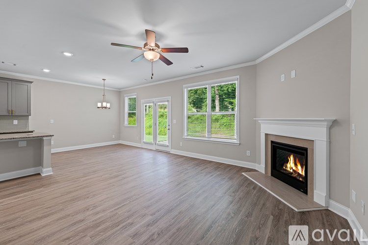 A spacious living room with a fireplace and a ceiling fan.