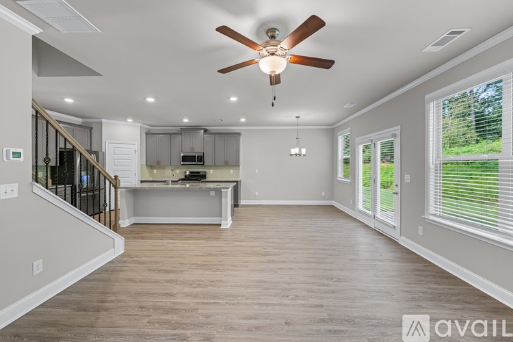 A spacious room with a ceiling fan and a kitchen area in the background.