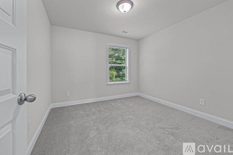 A room with a carpeted floor and a window with blinds.
