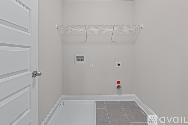 A white door is on the left of a room with a white wall and a white floor.